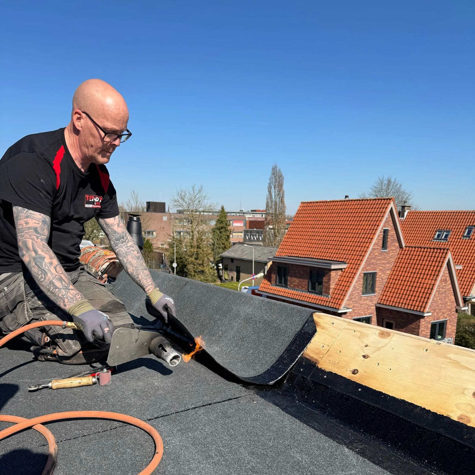 Dakdekker brandt bitumen langs de dakrand